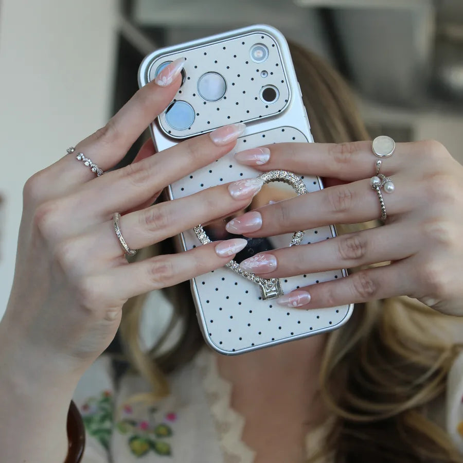 Taking a mirror selfie with a phone, wearing soft pink hand-painted press-on nails