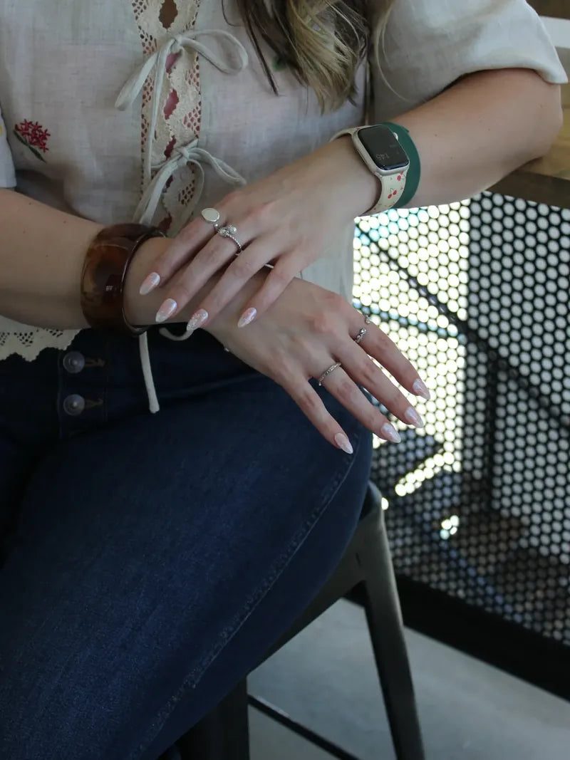 Wearing soft pearl press-on nails with rings and a tortoiseshell bangle